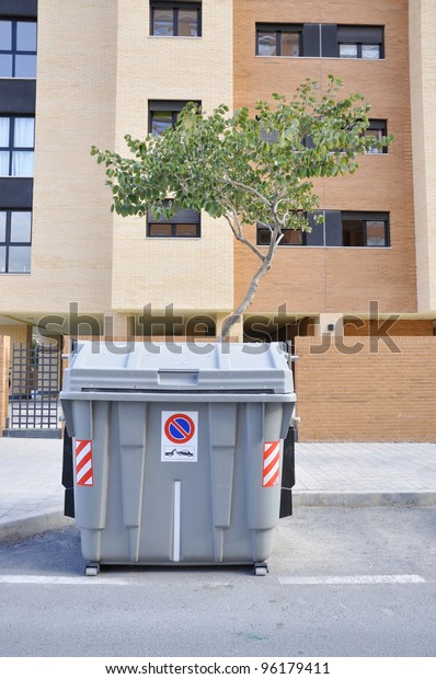 Trash\
Container with Recycle Social Awareness Symbol etched in English\
and Castillano Spanish Urban Lifestyle\
Scene.