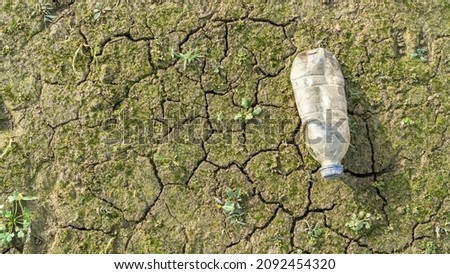 trash, empty old plastic water bottle abandoned on cracked soil ground in nature. Environmental pollution concept background with plastic bottle with selective focus