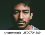 Trauma, portrait and Asian man in studio with depression, crisis or abuse isolated on black background. Dark, face and sad male person with stress, loss and grief with blank stare, war victim or pain