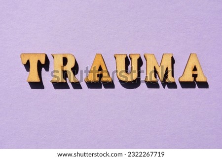 Trauma, word in wooden alphabet letters isolated on purple background as banner headline