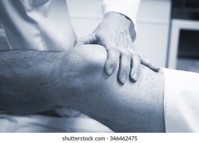 Traumatologist Orthopedic Surgeon Doctor Examining Middle Aged Man Patient To Determine Injury, Pain, Mobility And To Diagnose Medical Treatment In Leg, Knee Meniscus Cartilage, Ankle And Foot Injury