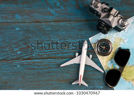 Travel accessories and items, passport travel documents photo camera sunglasses airplane mobile phone gumshoes travel guide map and globe on blue wooden background with copy space, top view.