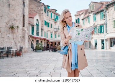 Travel And Active Lifestyle Concept. Young Traveller Woman Walking On Old Town Holding Tourist Map.