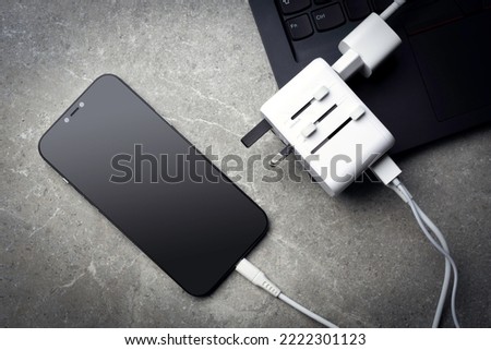 Travel adapter with phone and laptop on table.