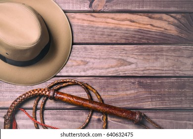 Travel And Adventure Concept. Vintage Fedora Hat And Bullwhip On Wooden Table. Top View.