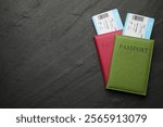 Travel agency. Flight tickets and passports on dark textured table, top view. Space for text