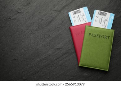 Agencia de viajes. Billetes de avión y pasaportes en mesa de textura oscura, vista superior. Espacio para texto