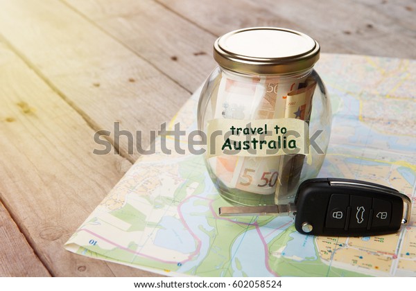 Travel\
Australia by car - money jar, car key and\
roadmap