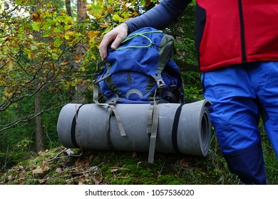 Travel Backpack In The Forest And A Man Hicker Near It. Pausa During Hicking In Forest.