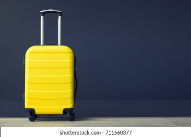 Travel bag against the wall. Yellow suitcase.