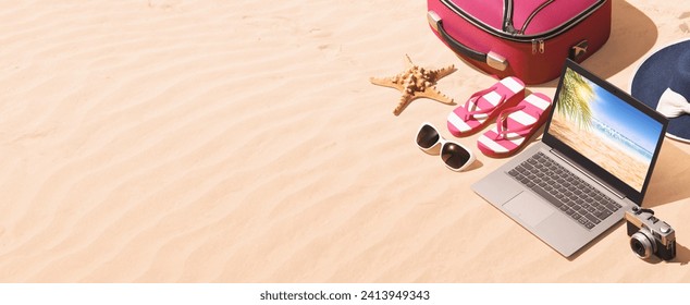 Travel bag, beach accessories and laptop on the sand, summer vacations concept - Powered by Shutterstock