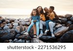 Travel, beach and family sitting on rocks while on summer vacation, adventure or weekend trip. Happy, smile and portrait of mother bonding with her children and husband by the ocean while on holiday.
