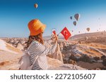 a travel blogger girl takes photos of flying balloons in Cappadocia and the Turkish flag. Social media influencer