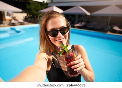 Travel Blogger Woman In Bikini Taking Selfie Photo With Cocktail Near Swimming Pool. Pov Of Lifestyle Vlogger Selfie From Vacation On Luxury Resort. Female In Swimwear Drinks Beverage On Tropical Spa.