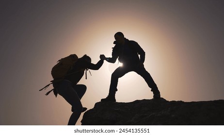 Travel bonding, friend gives hand on rock. Nature trek, travel friend rock climbing. Silhouetted rock ascent, friend in nature. Travel adventure, rock climbing with friend. Teamwork nature mountain - Powered by Shutterstock