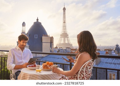 Travel, breakfast and couple in Paris with the Eiffel Tower on a terrace for romance or anniversary. City, vacation or tourism tech app with a man and woman eating food while looking at a view