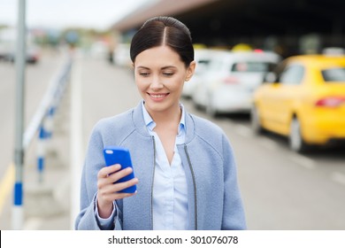 Travel, Business Trip, People And Tourism Concept - Smiling Young Woman With Smartphone Over Taxi Station Or City Street