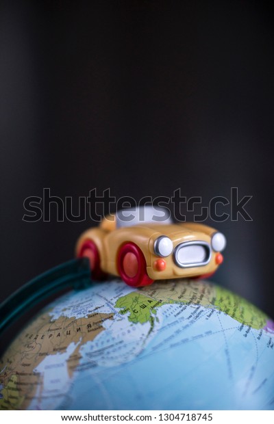 Travel\
by car concept. Toy car on the model of the\
globe.