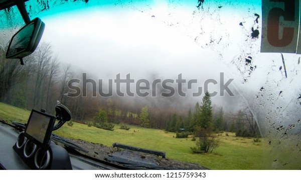 Travel by car in the mountains. Offroad The\
view from the window on the foggy mountains and forests of the\
Ukrainian Carpathians