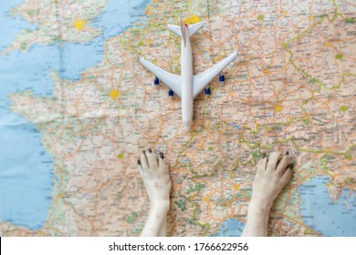 Travel By Plane With Dog. Pet Small Paws On The Table Planning Trip To Europe. Blurred Map Top Table View. Toy Plane. Globetrotter Traveler Searching For Adventure 