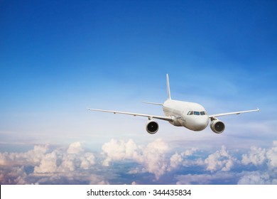 Travel By Plane, International Flight, Airplane Flying In Blue Sky Above The Clouds