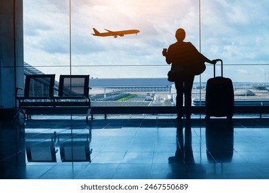 travel by plane, woman passenger waiting in airport, silhouette of passenger watching aircraft taking off - Powered by Shutterstock