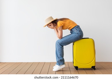 Travel Cancel Concept. Upset Young Woman Sitting On Suitcase And Closing Face With Hands, Feeling Unhappy Because Of Cancelled Summer Journey, Light Wall Background, Free Space