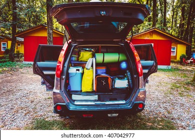 Travel car and camping luggage packed in the full car trunk. Outdoor wanderlust items. Outdoor, adventures and travel suv. Ready to go concept. Vintage hipster tone. Camping exploring.