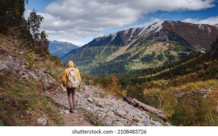travel to Caucasus mountains in Karachay-Cherkessia, Arkhyz. Man in yellow hipster hoodie hiking in mountains with travel backpack. Wandering lifestyle, adventure concept autumn vacation in wild - Shutterstock ID 2108483726