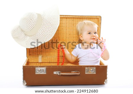 Travel, children, vacation - concept. Cute funny baby playing in sunglasses and summer straw hat looks out of a suitcase