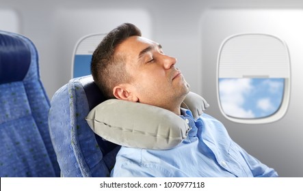 Travel, Comfort And People Concept - Man Sleeping In Plane With Inflatable Cervical Neck Pillow Over Porthole Background