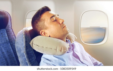 Travel, Comfort And People Concept - Man Sleeping In Plane With Inflatable Cervical Neck Pillow Over Porthole Background