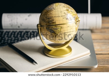 Travel composition with globe, laptop and notepad.
