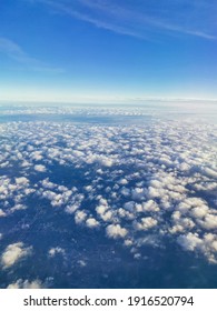 Travel Concept. A Beautiful View From An Airplane On White Voluminous Fluffy Clouds Against The Background Of A Bright Blue Sky, City Skyscrapers Below, Top View, Vertical Frame