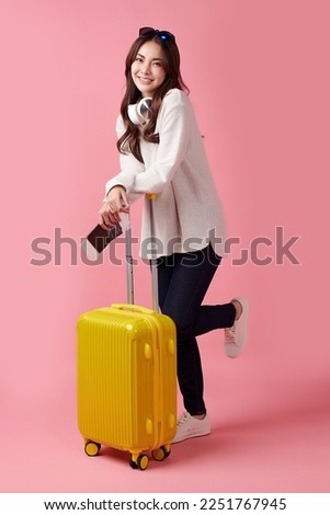 Travel concept. Beautiful Young Asian female tourist sit with suitcase, on pink background.