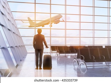 Travel Concept With Businessman And A Suitcase In Airport Interior With Plane Flying By. 3D Rendering