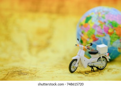 Travel Concept. Close up of vintage motorcycle toy on map with mini world ball.