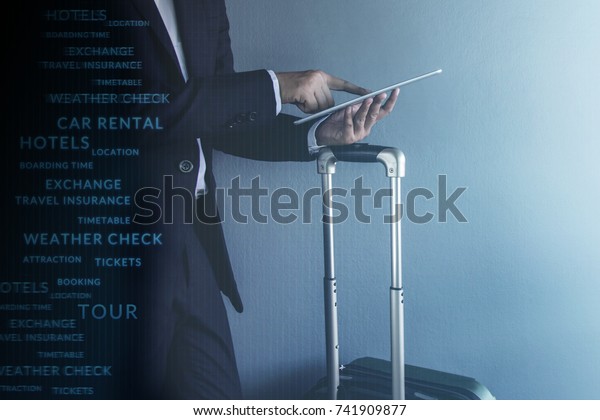 Travel Concept, Graphic about Travel\
Technology on Modern Businessman wearing suit and touching a\
digital tablet at grey wall in the airport, Side\
view
