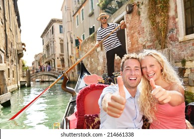 Travel concept - happy couple Venice gondola giving thumbs up hand sign excited looking at camera. Romantic young beautiful couple on vacation holidays sailing in venetian canal in gondole. Italy