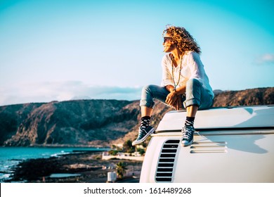 Travel concept with independent people enjoyig the outdoor leisure activity and wanderlust life lifestyle - woman sit down on the roof of a old nice vintage camper van