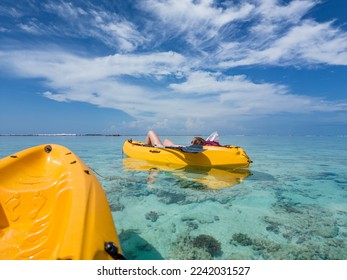 Travel concept - kayaking in sea at Maldives.
Yellow kayaks in blue sea at summer. Woman relaxing on floating canoe in clear azure water. 