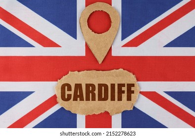 Travel concept. On the flag of Great Britain lies a symbol of geolocation and cardboard with the inscription - Cardiff