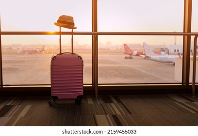 Travel concept with Pink luggage as hat in the airport terminal waiting area, summer vacation concept, traveling and enjoying concept - Shutterstock ID 2159455033