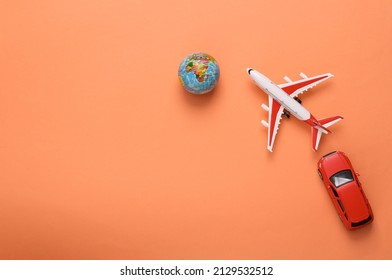 Travel concept. Toy model of car and airplane, globe on coral-colored background. Top view. Copy space - Powered by Shutterstock