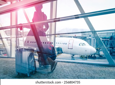 Travel concept with woman and suitcase moving fast to airport terminal gate - Double exposure look with focus on the aircraft in the background - Violet marsala sun flare with vintage filter editing - Powered by Shutterstock