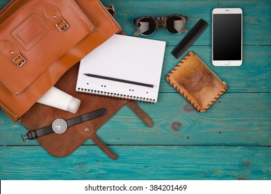 Travel Concept - Women Set With Bag With Phone, Notepad, Purse, Watch, Glasses On Blue Wooden Background. Top View