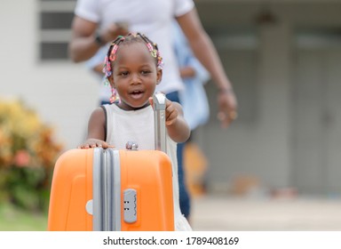 Travel Concepts, Orange Luggage With Blurred Cheerful African American Girl And Parent Family Leaving House For Vacation