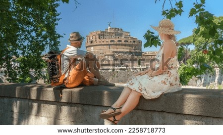 Travel Couple looking at Mausoleum of Hadrian or Castel Sant'Angelo at the Tiber River, Rome, Italy, Europe