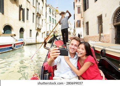 Travel Couple Taking Selfie Picture In Gondola On Venice Vacation. Beautiful Lovers On A Romantic Boat Ride Across The Venetian Canals Taking Self-portrait Pictures With Smartphone During Holiday.