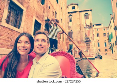 Travel couple in Venice on Gondola ride romance in boat talking happy together on travel vacation holidays. Young multiracial couple sailing in venetian canal in gondole. Italy, Europe